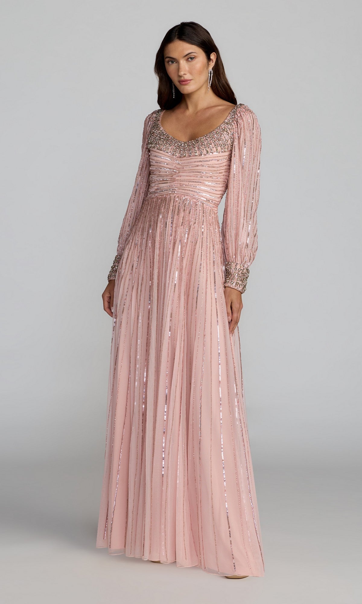 A woman wearing the Mac Duggal 23085 Long Formal Dress in Light Rose, featuring beaded embellishments on the neckline, sleeves, and cuffs, stands against a plain background.